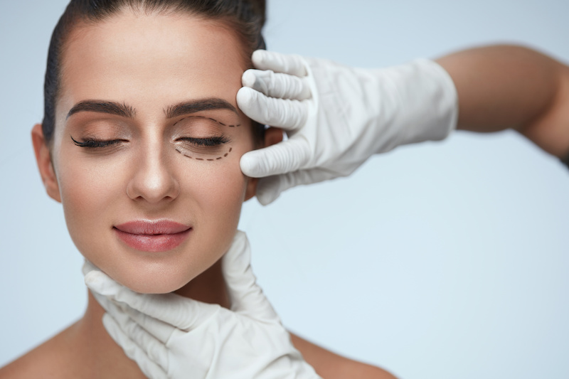 woman with markings on her face and doctor with gloves touching her face