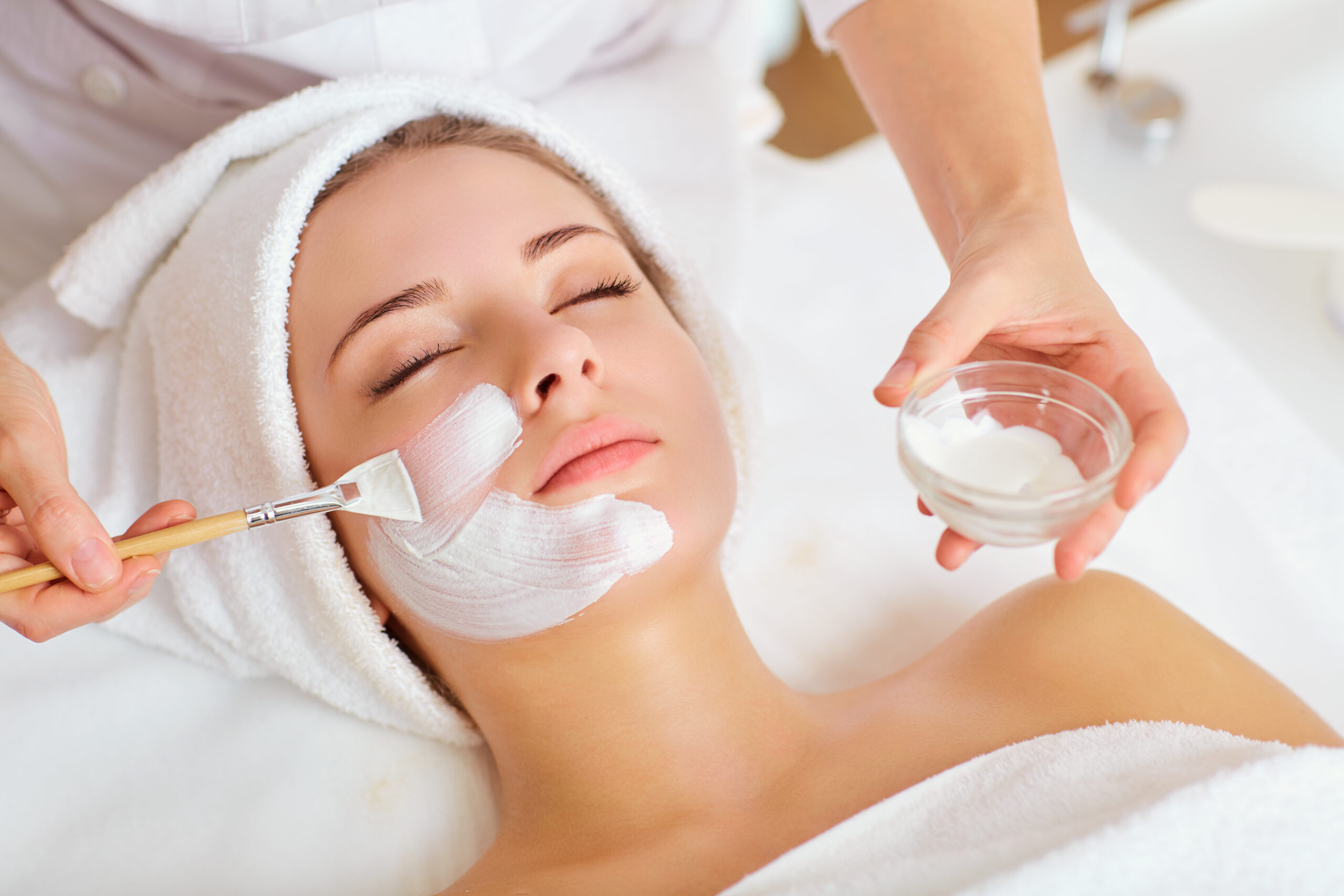 Beautician doing injections dermal fillers into female cheeks